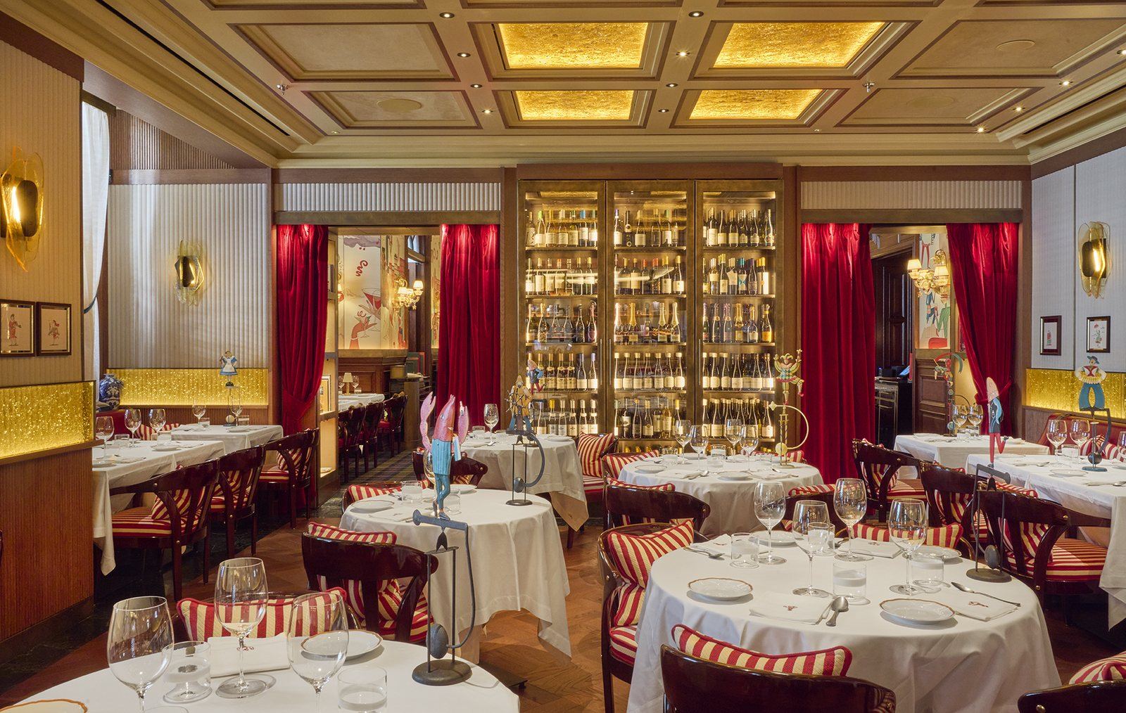The bar at Langosteria London: walnut counter, red stools and a gold wine wall